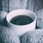 Gloved hands holding a hot cup of coffee on a cold day