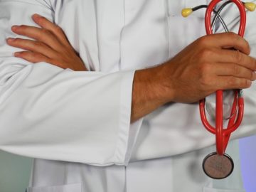 doctor in white coat holding stethoscope