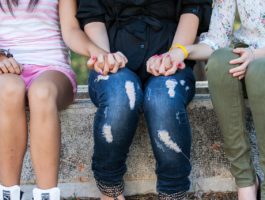 Young people sitting on a wall and holding hands