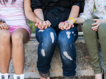 Young people sitting on a wall and holding hands